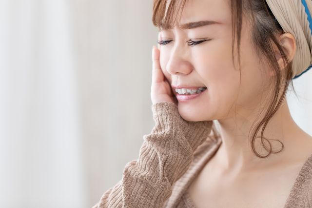 むし歯の痛みを感じる女性